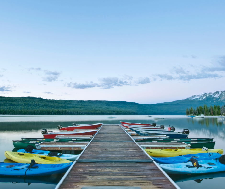 Summer camp dock on the lake lined with kayaks on either side.