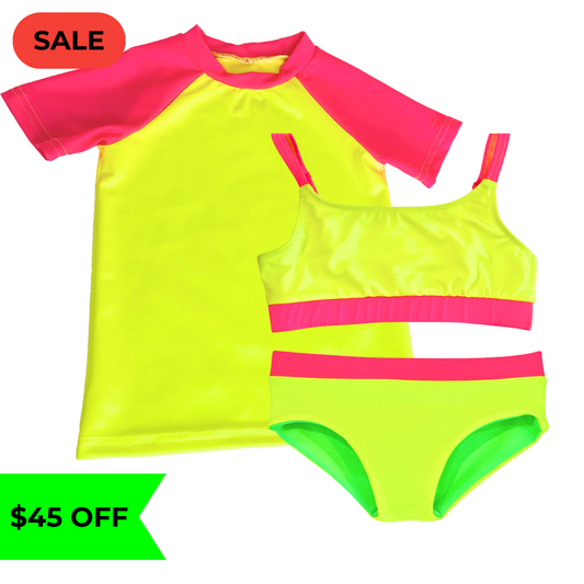 Bright neon yellow UPF short sleeved sun shirt rash guard  with neon pink sleeves paired with a girls' swimsuit featuring neon yellow and neon pink accents, along with reversible bikini bottoms in neon yellow and neon green. This hi vis swimsuit is designed for high visibility, allowing the swimmer to stand out from any background."