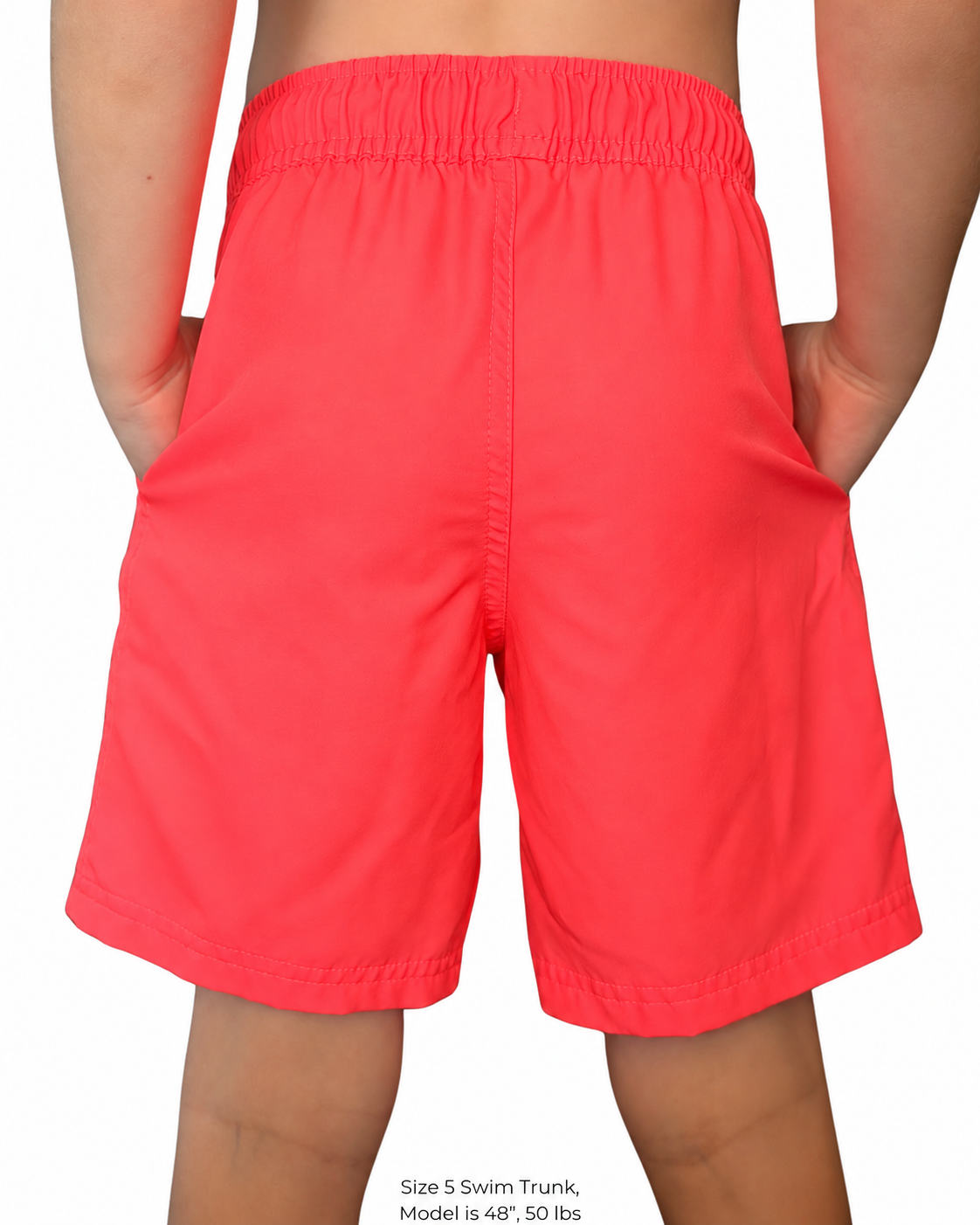 Boy wearing hiviz neon pink swim trunks with hands in pockets.