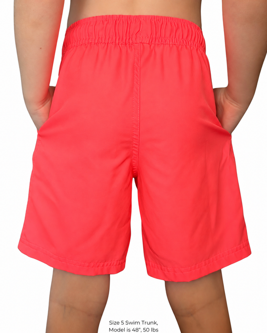 Boy wearing hiviz neon pink swim trunks with hands in pockets.