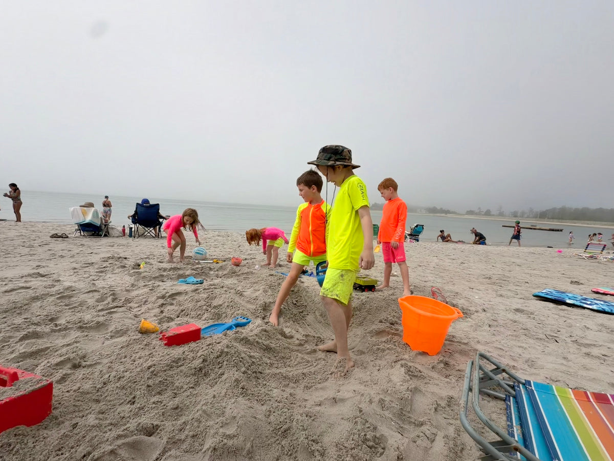 Kids at the beach wearing hi-viz neon rash guards the best rash guard color for safety
