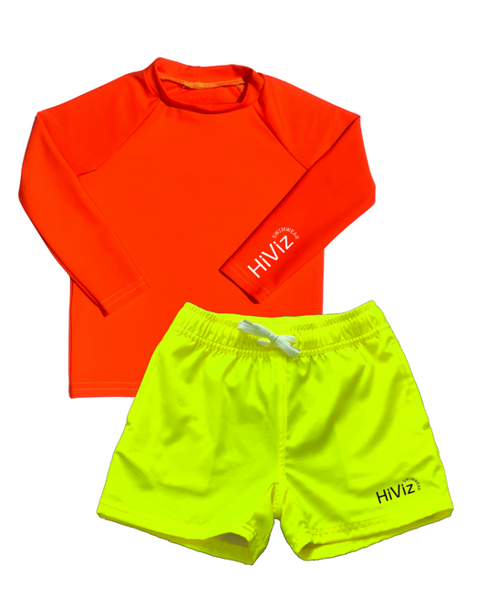 A product photo of a boys neon rash guard in neon orange paired with bright boys swim trunks. The hi vis neon yellow swim shorts have a boxer brief lining for anti-chaffing.  The boys neon yellow bright swim trunks stand out against any background. 
