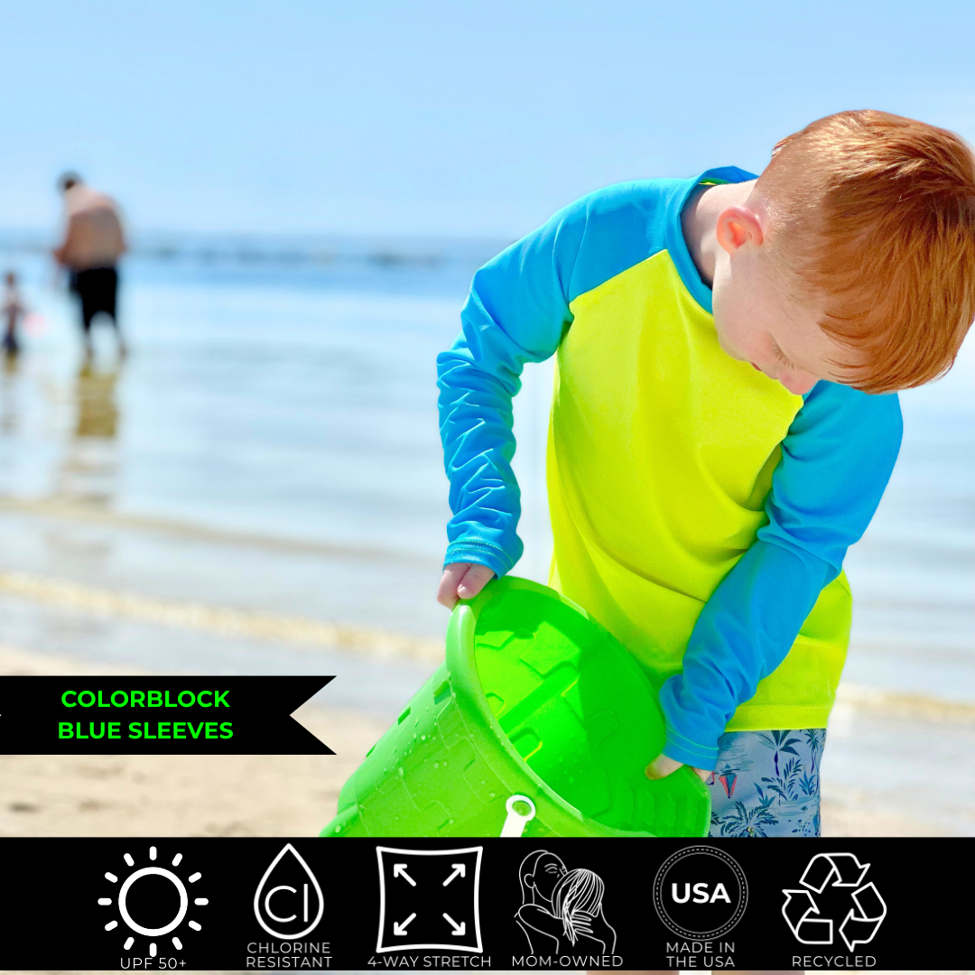 Kids neon swimwear, neon yellow rash guard with blue sleeves. The bright swimwear stands out againt the dull background. 