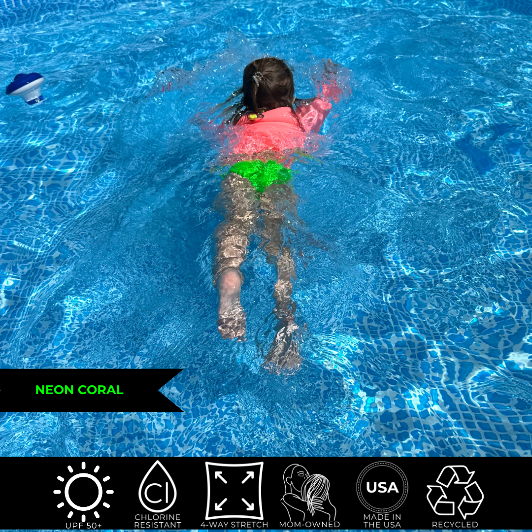 Photo of a girl in a pool swimming away. She is wearing a neon pink rash guard and neon green swim bottoms. 