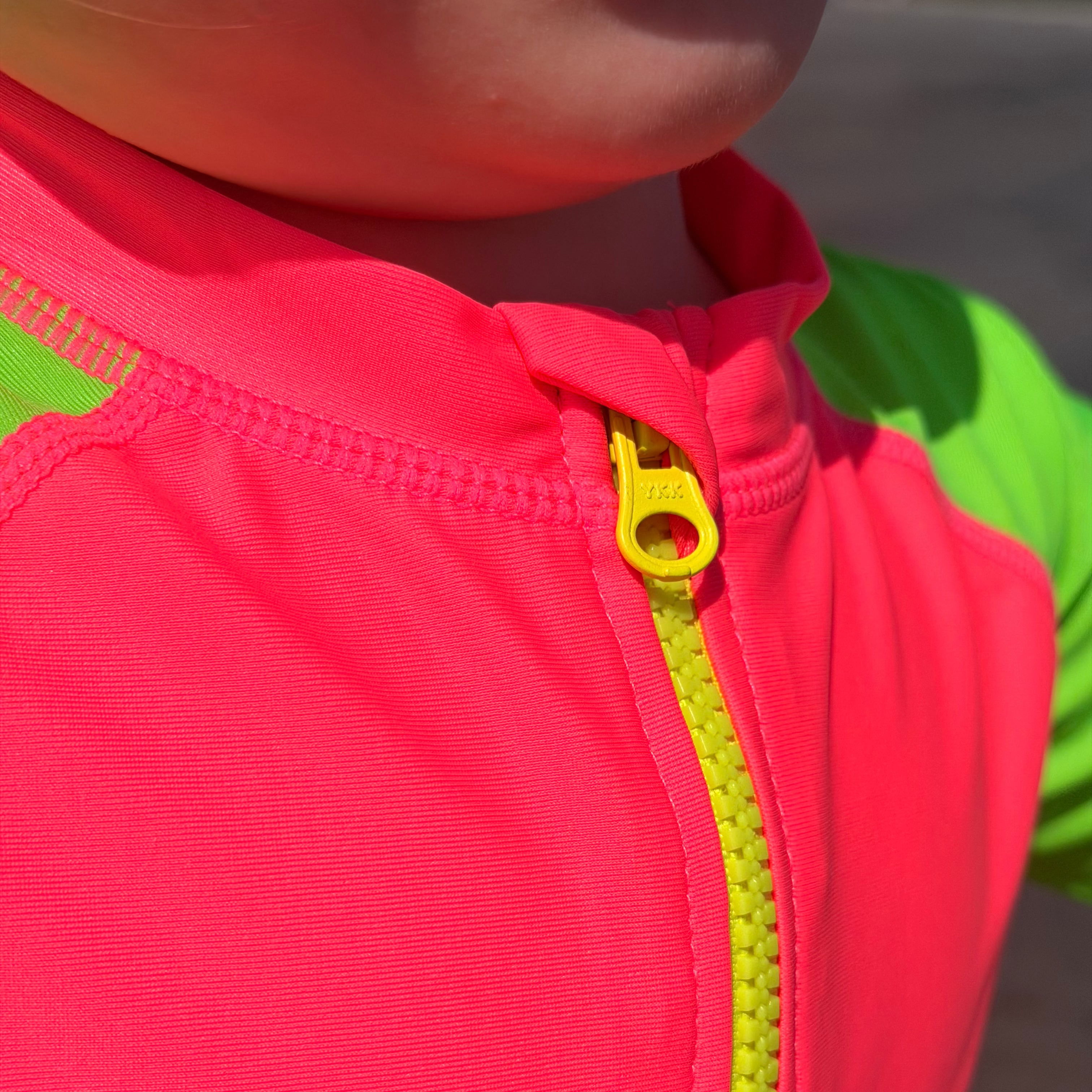 Close-up of a bright pink jacket with a yellow zipper on a blurred background