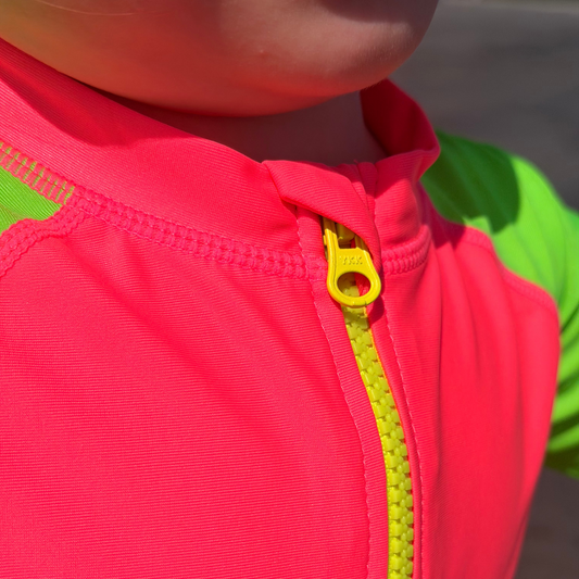 Close-up of a bright pink jacket with a yellow zipper on a blurred background
