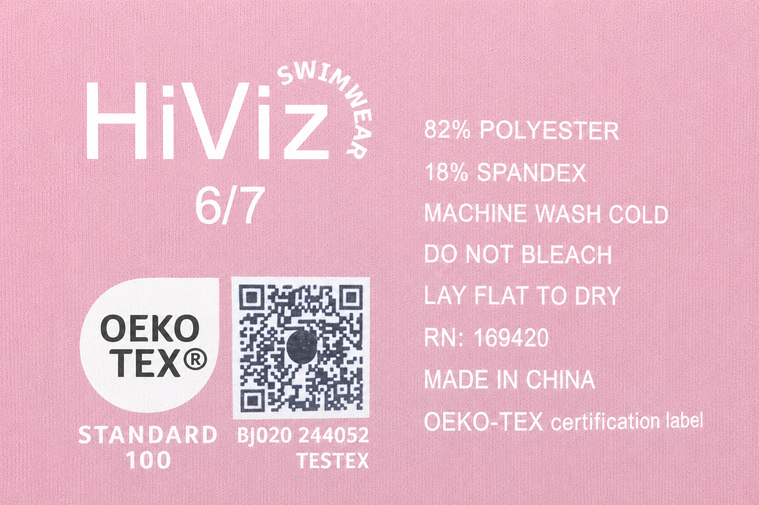 Close-up of HiViz Swimwear printed garment label on light pink fabric featuring OEKO-TEX Standard 100 certification, QR code, care instructions, and fabric composition details.