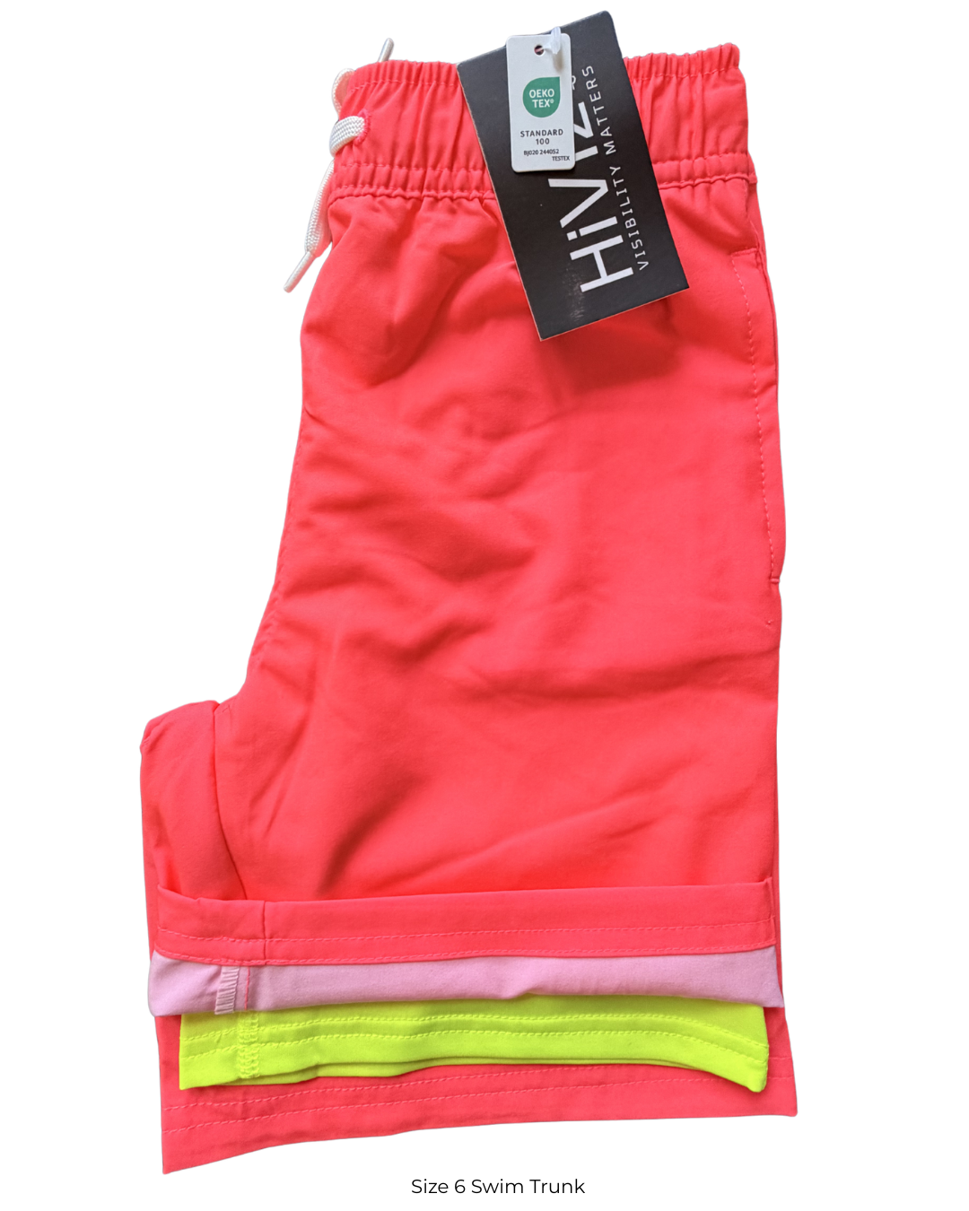 Kids neon swim trunks in bright coral with boxer brief liner, elastic waistband and drawstring, folded to show neon yellow liner and Oeko-Tex Standard 100 tag