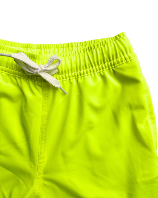Close-up of neon yellow swim trunks boys shorts with a white drawstring and elastic waistband on a white background.